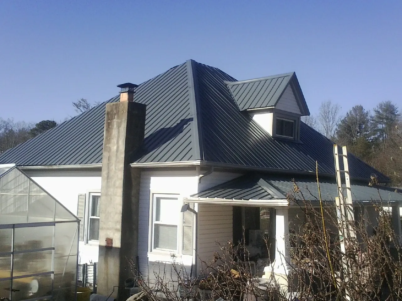 Dark blue standing seam metal roof on a white farmhouse with dormer — Slate & Tile Roof Repair by Roofing Brothers in Farmville