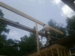 Carpenter setting a ridge beam over a new addition frame — Ice Dam Removal by Roofing Brothers in Farmville