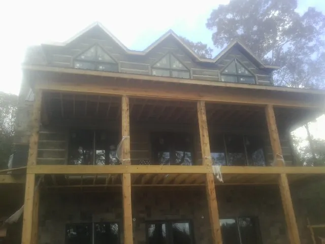 Dormers and porch framing on a large log home under construction — Roof Coating work by our crew in Farmville